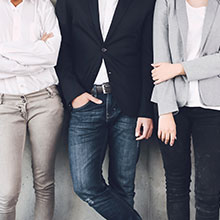 Drei Angestellte stehen an einer Wand.